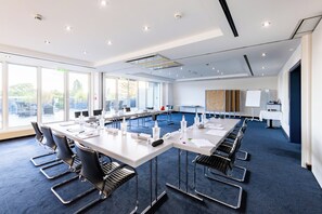 A conference room with a long table, chairs, and a whiteboard. - Hotel Alexander am Zoo (Frankfurt)