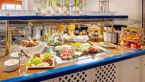 A buffet with various food items, including fruits, cheeses, and meats, arranged on a counter with a blue edge. - Hotel Alexander am Zoo (Frankfurt)