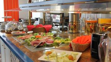 A buffet with various food items, including meats, cheeses, and fruits, and a coffee machine.