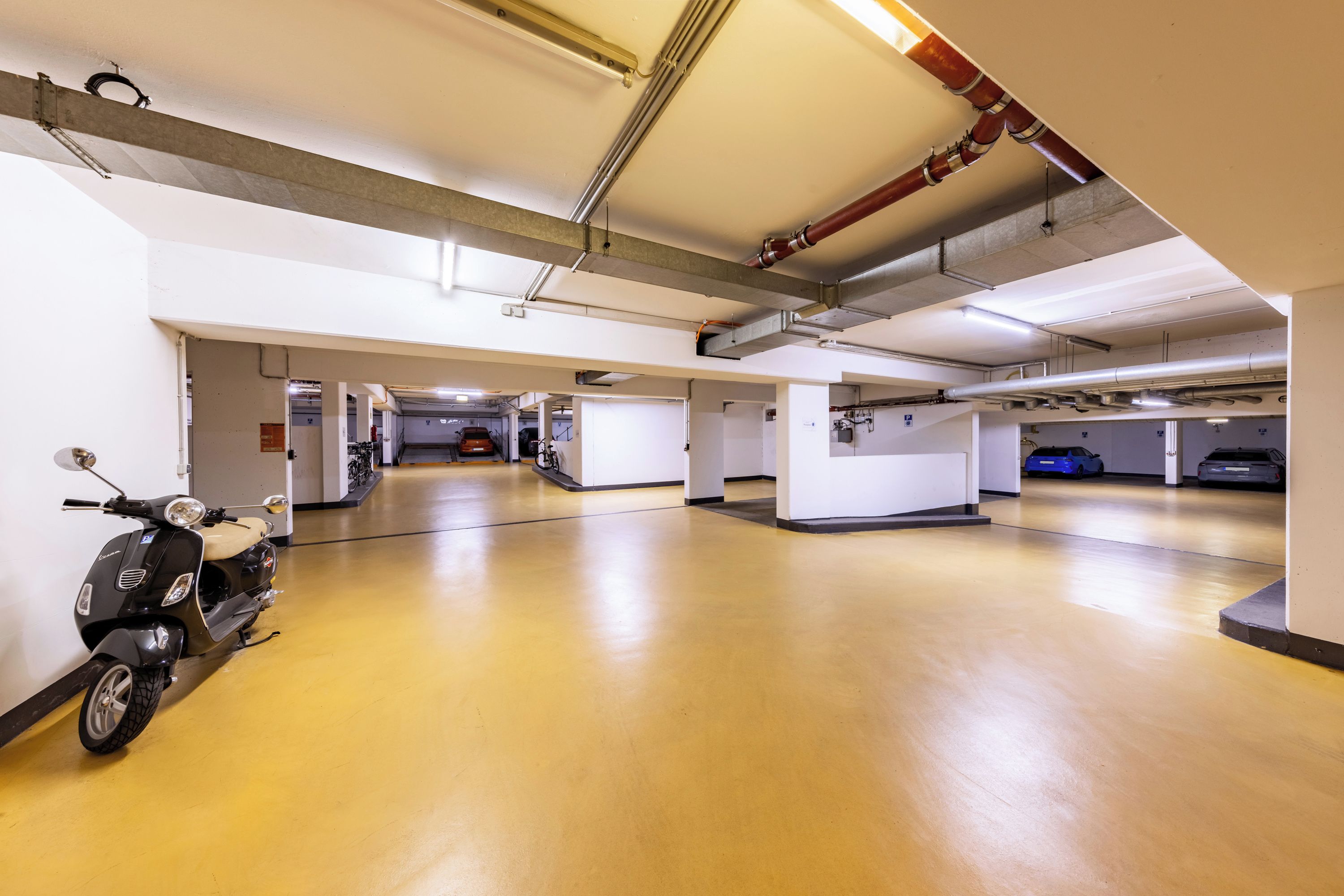 Eine Parkgarage mit mehreren Ebenen, Betonböden und einem Roller im Vordergrund.
