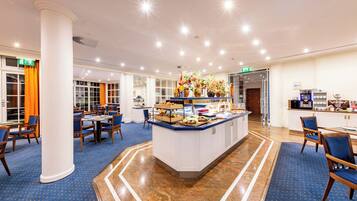 Ein Hotel-Speisesaal mit einem zentralen Buffet, verschiedenen Sitzgelegenheiten und einem modernen Innenraum.