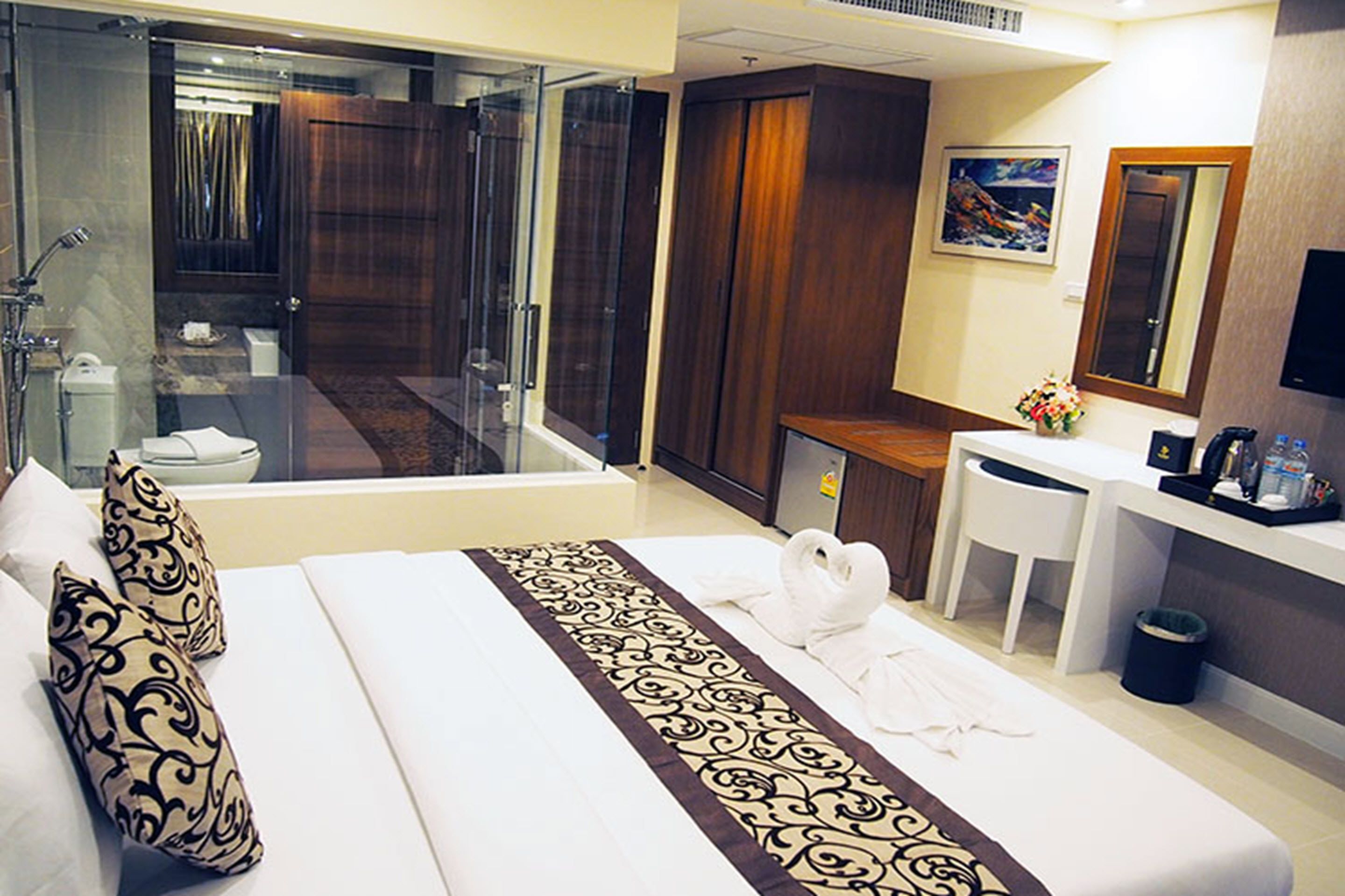 Une chambre d’hôtel avec un grand lit, une salle de bain avec une douche en verre, un bureau et une télévision.