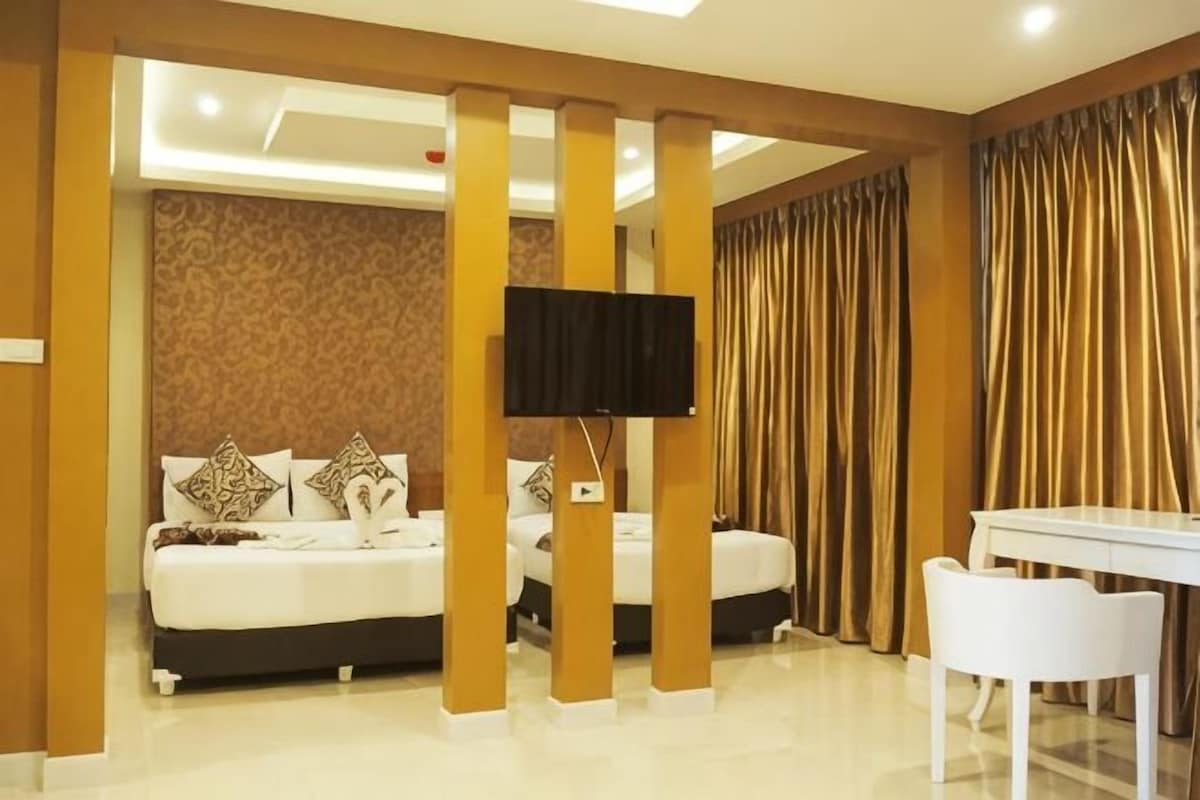 Una habitación de hotel con una cama, televisión, escritorio y cortinas.