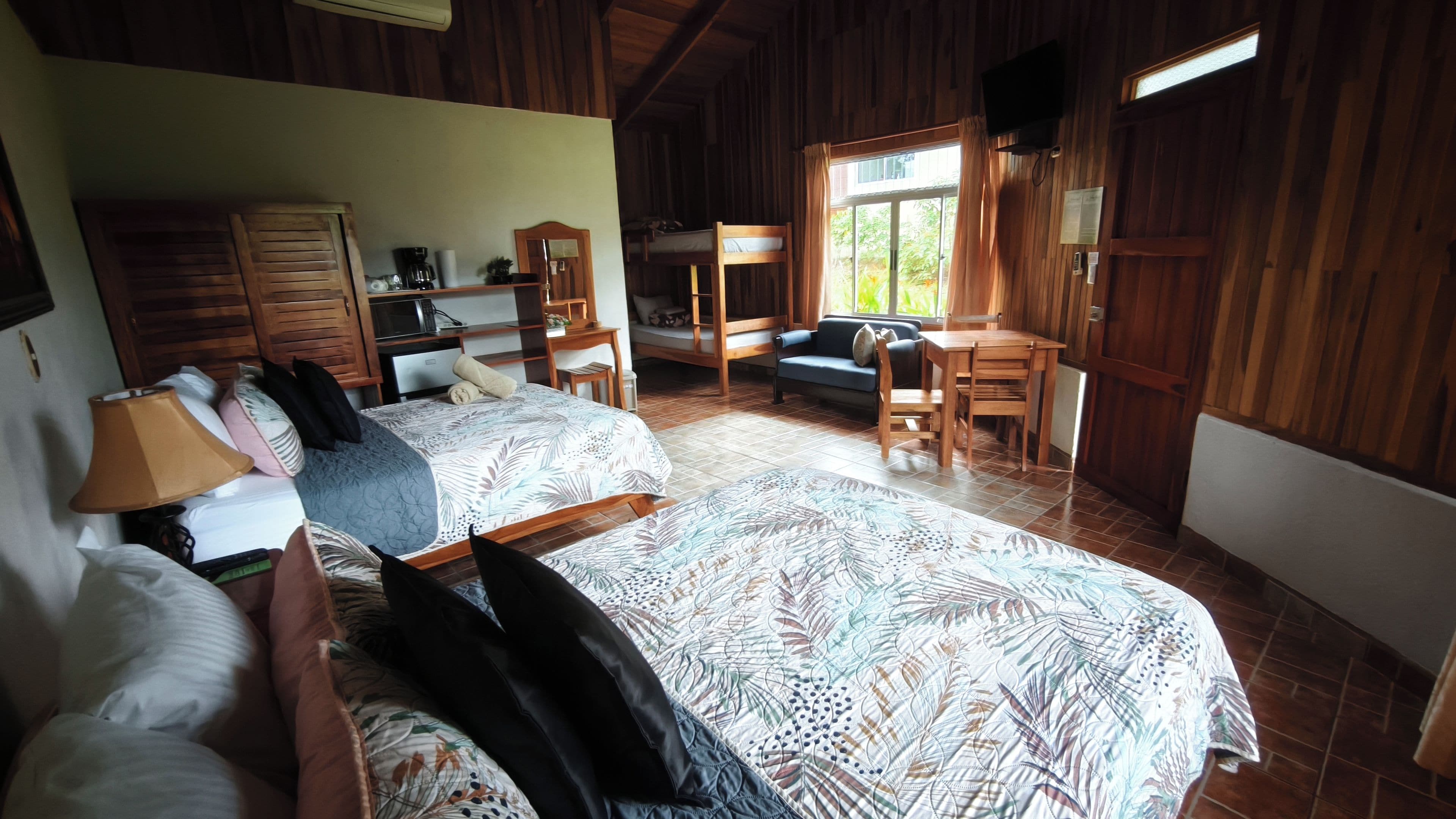 A room with two beds, a desk, a chair, and a television.