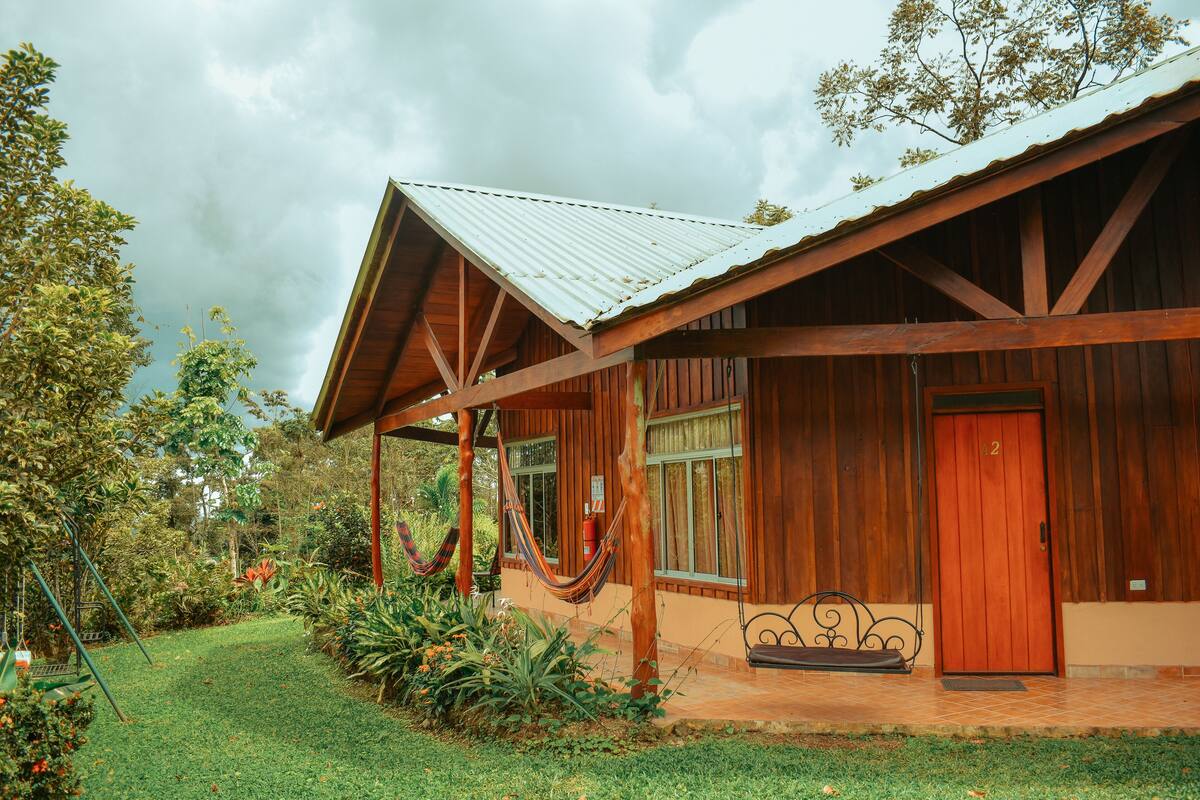 A wooden house with a porch, a hammock, and a door marked with the number 2.