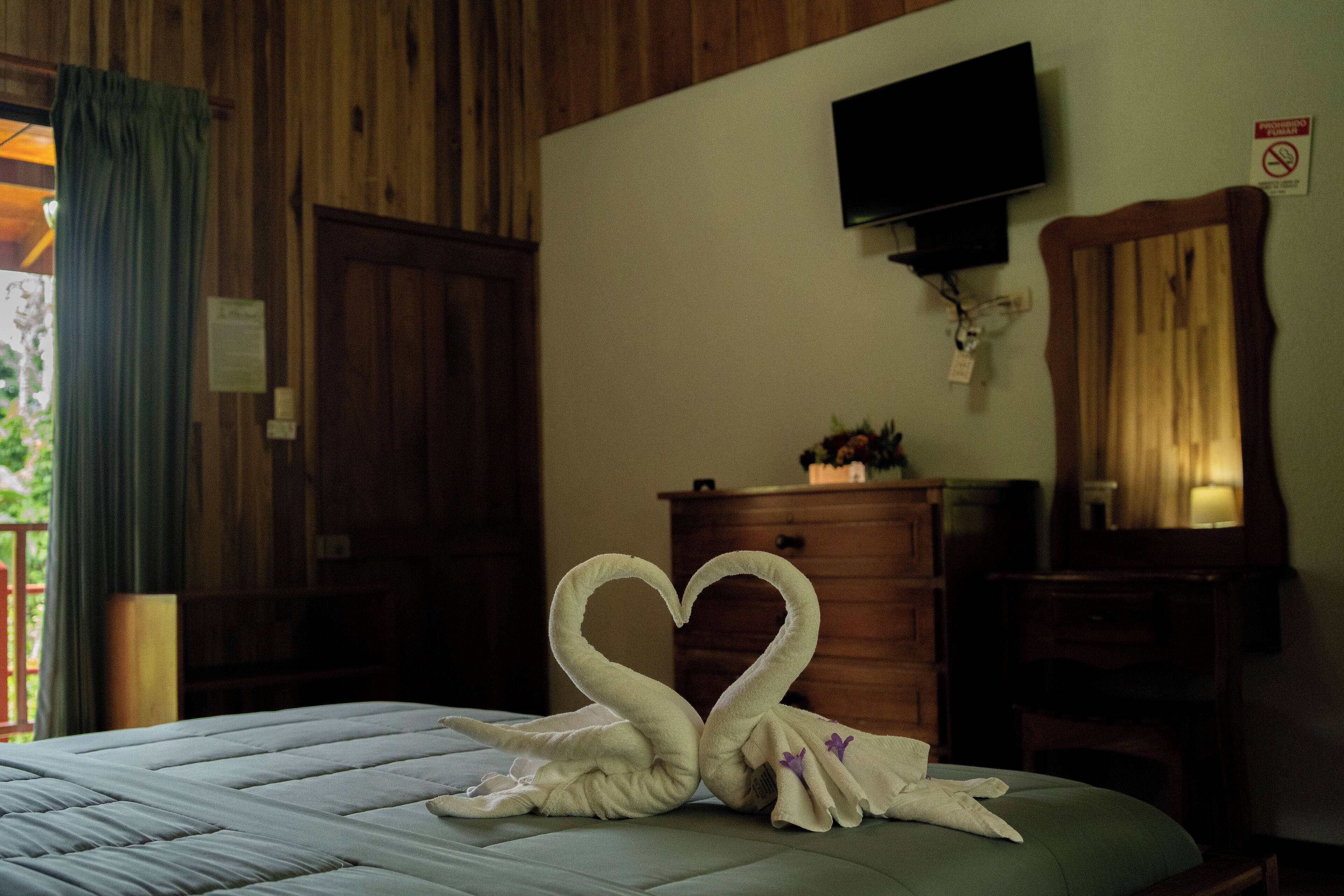 A hotel room with a bed, a dresser, a television, and a mirror.