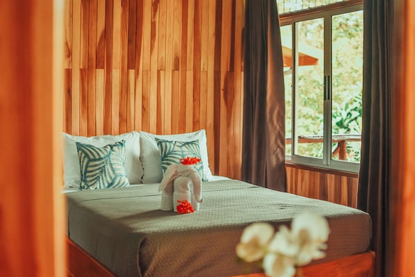 A neatly made bed with a green bedspread, white pillows, and a decorative stuffed animal. - Brisas Arenal Hotel (La Fortuna)