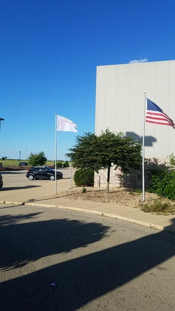 A parking lot with two flags, a building, and a tree.