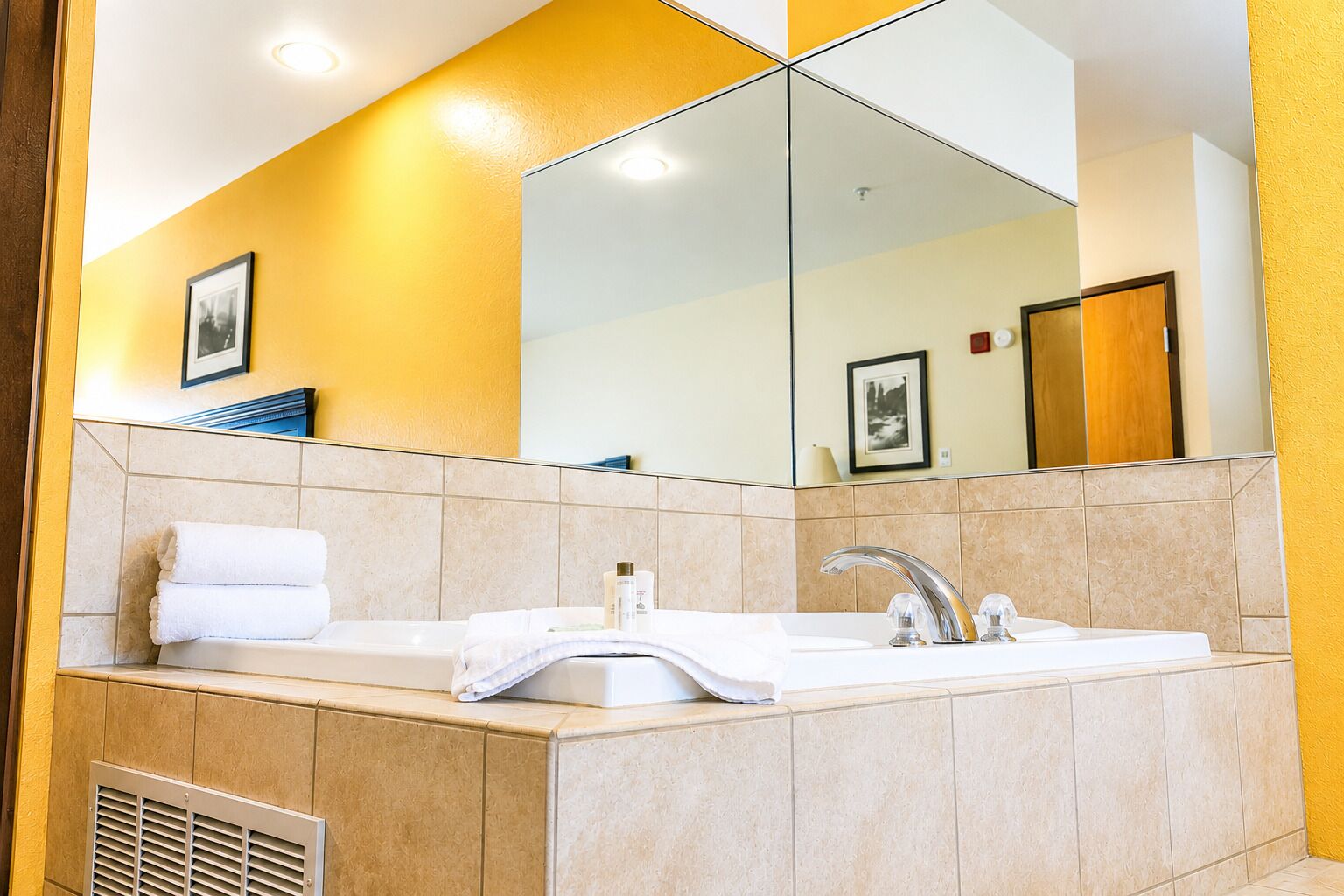 A bathroom with a bathtub, a sink, and a large mirror.