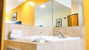 A bathroom with a bathtub, a sink, and a large mirror.