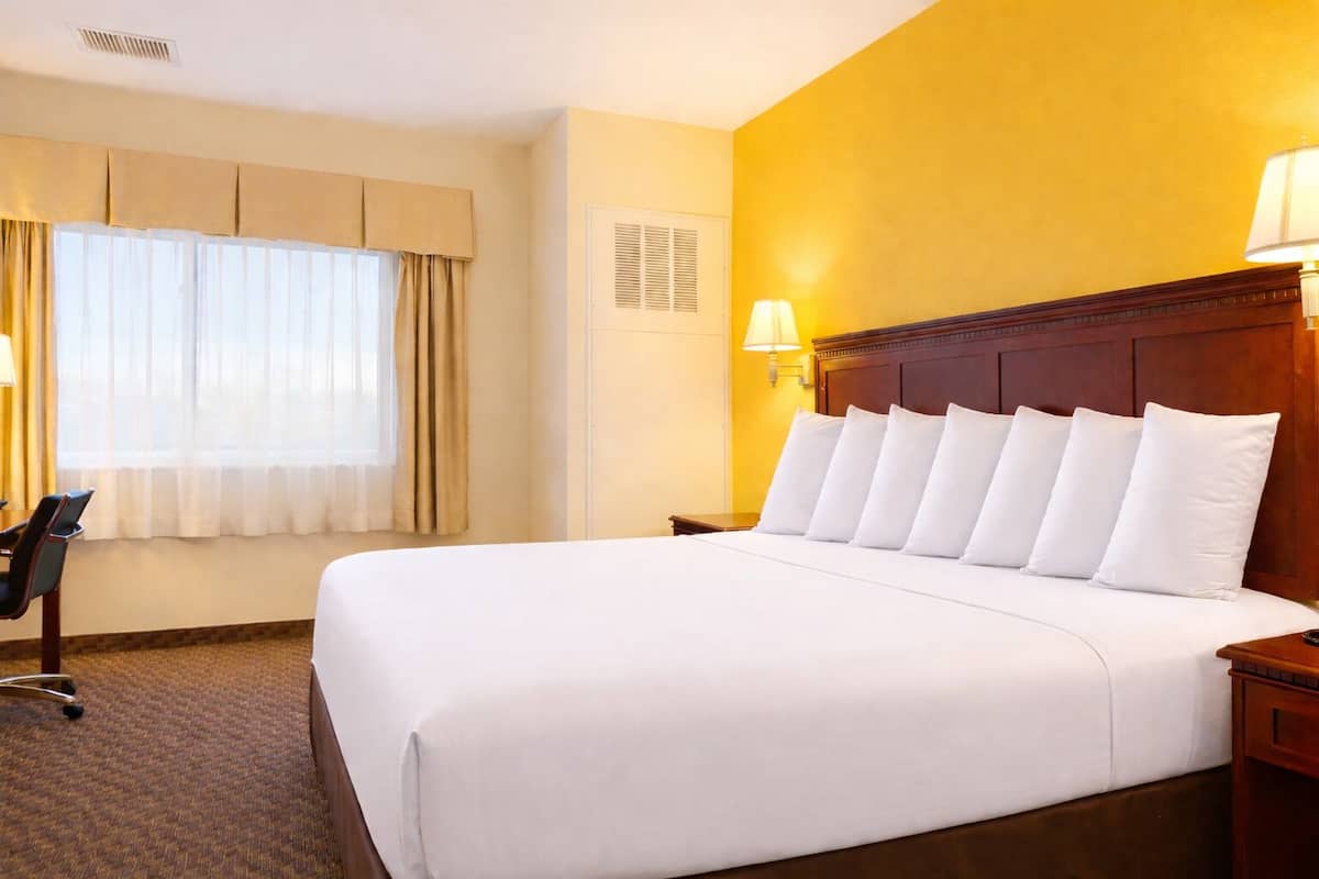 A hotel room with a large bed, a desk, and a chair.