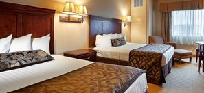 A hotel room with two beds, a wooden headboard, a desk, and a chair.