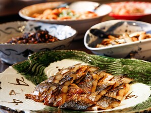 A variety of dishes on a table, including grilled fish and other foods. - Shimahana (Sumoto)