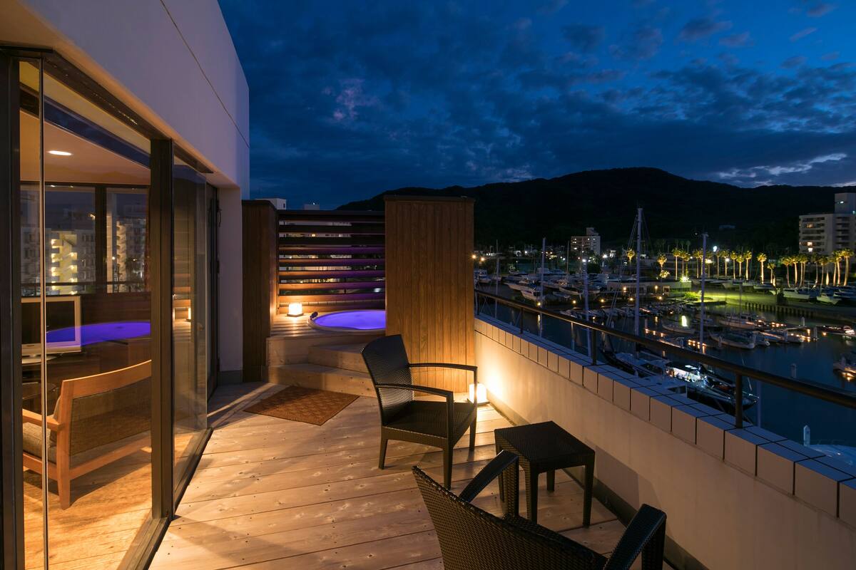 A balcony with a view of a marina and mountains at dusk.