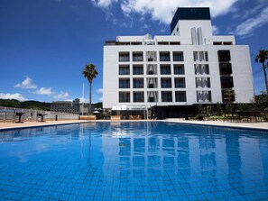 A modern hotel with a swimming pool, outdoor seating, and a view of the surrounding landscape. - Shimahana (Sumoto)