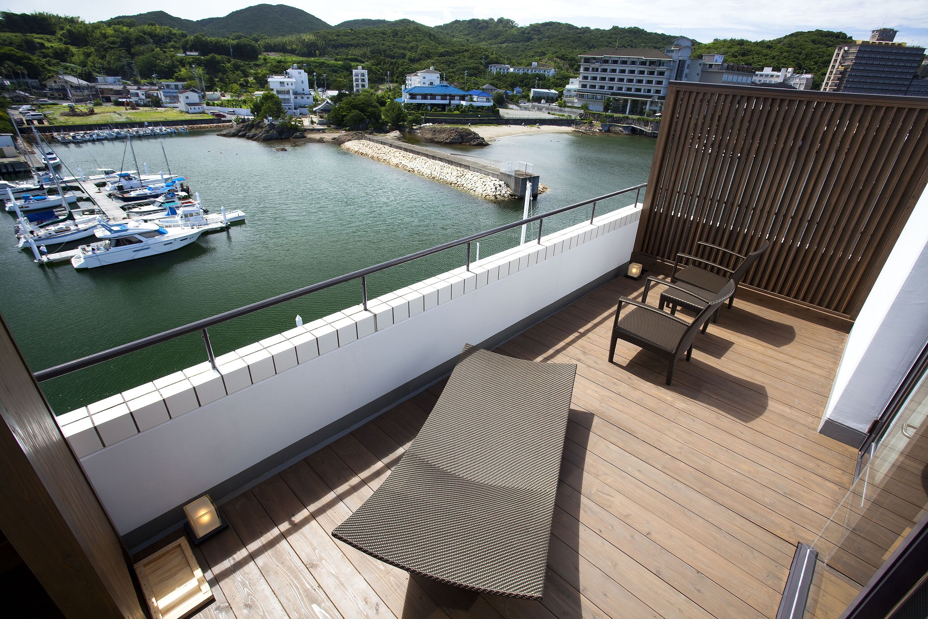 A balcony with a view of a marina, a wooden deck, and a seating area.