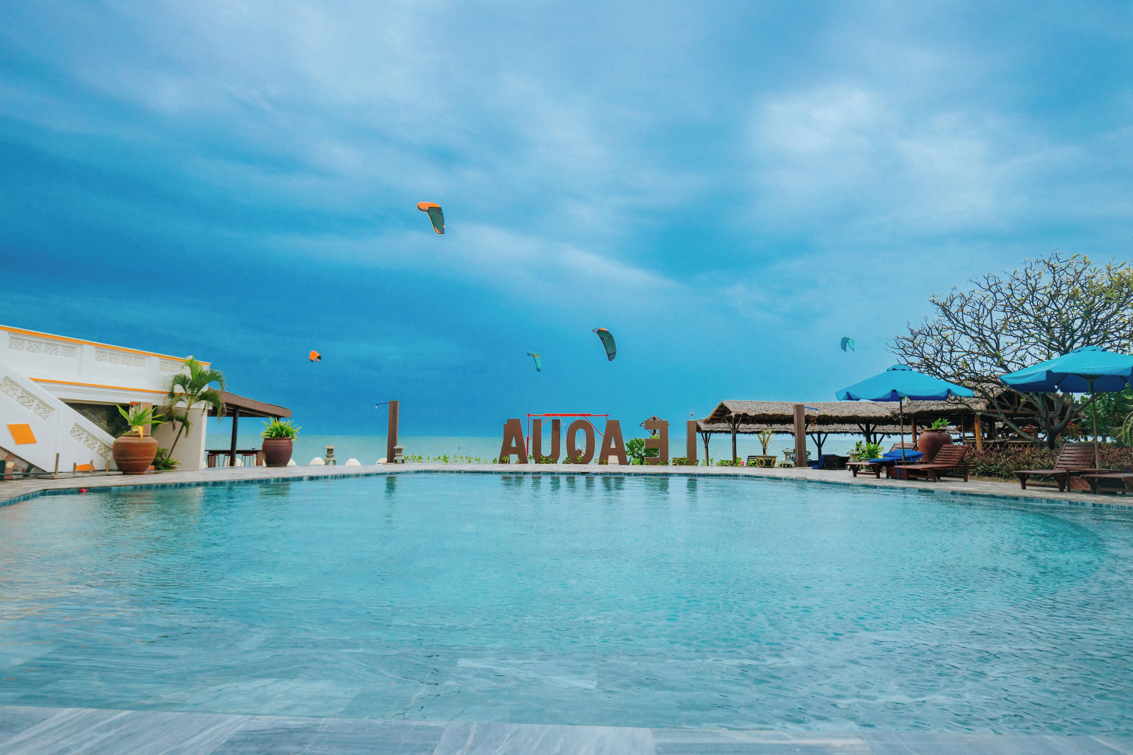 A swimming pool with lounge chairs and umbrellas, and the word 'AQUA' in the background.