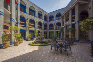A courtyard with a fountain, potted plants, and outdoor seating. - Hotel La Silla (Monterrey)