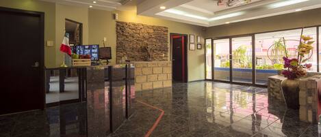 A lobby with a stone wall, a reception desk, and a large window.