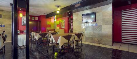 A restaurant with a marble floor, a counter with chairs, and a TV on the wall.