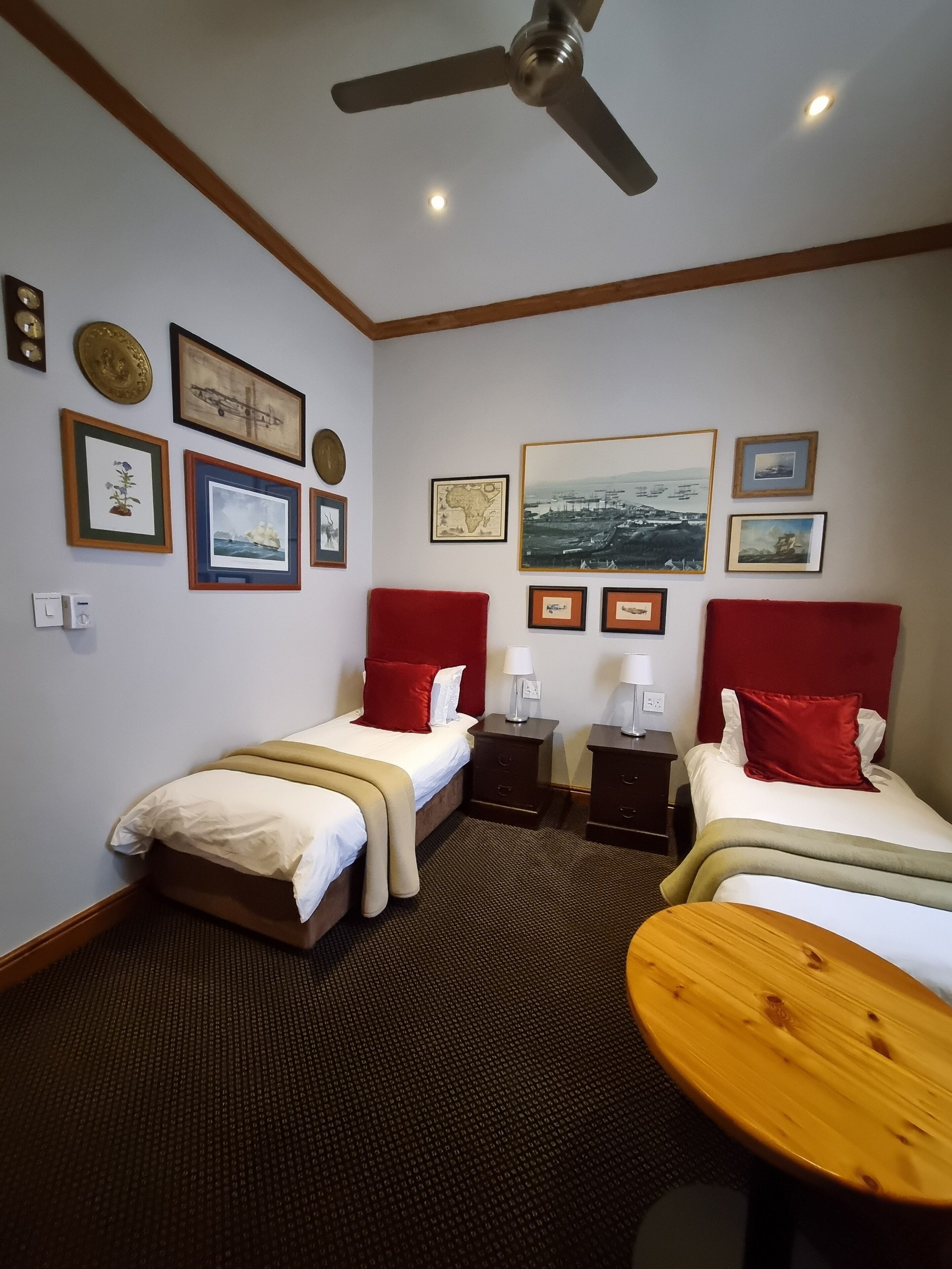 Une chambre d’hôtel avec deux lits, un ventilateur de plafond, une grande fenêtre et une table à manger.