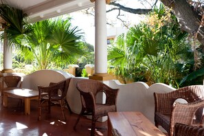 A covered outdoor seating area with wicker furniture and a view of lush greenery. - Ashanti Guest House Gardens (Cape Town)