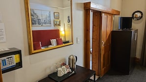 Habitación de hotel con un espejo grande, un escritorio con hervidor, un minibar y un armario.