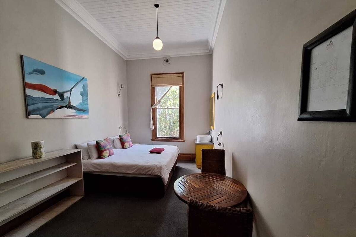 Een slaapkamer met een bed, een raam, een bureau en een stoel.