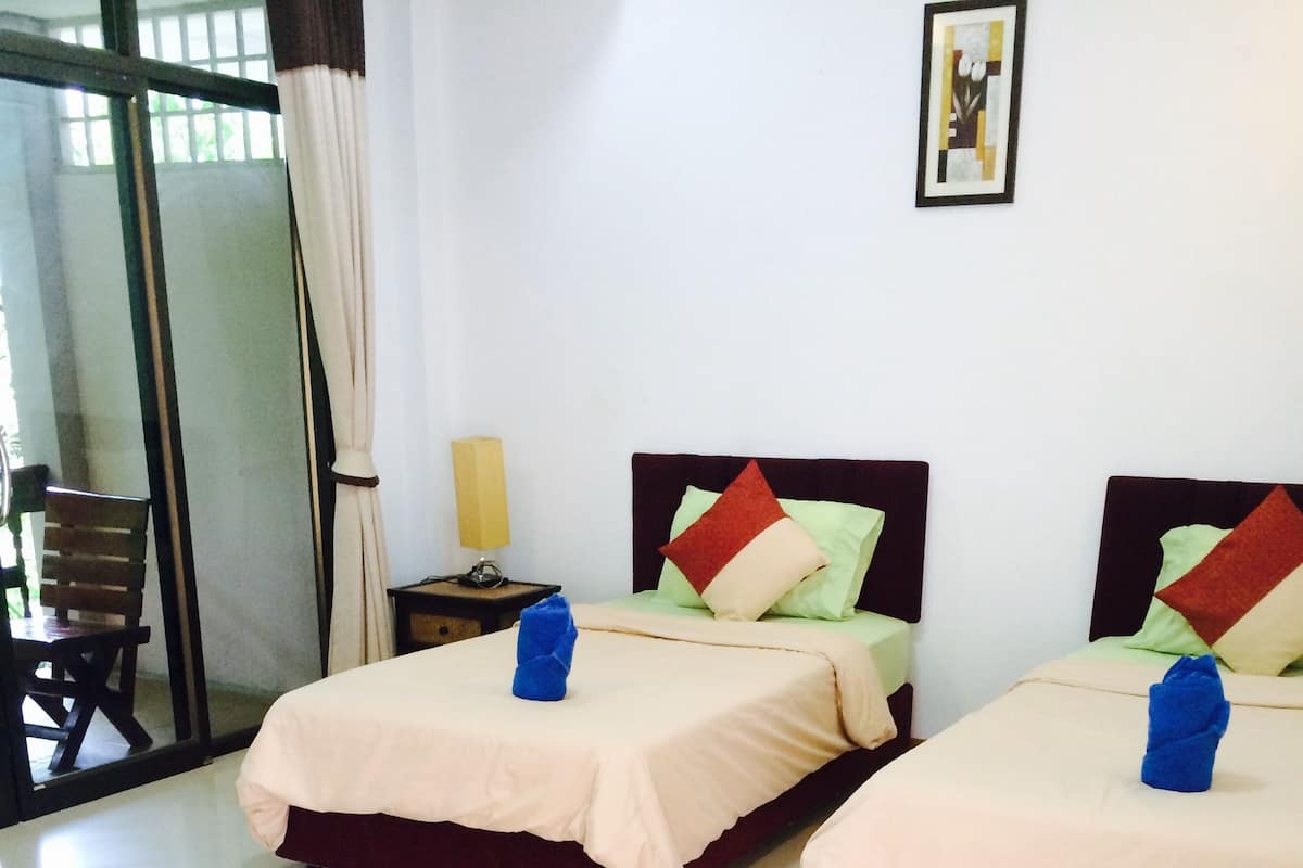 Habitación de hotel con dos camas, cada una con una toalla azul, una lámpara y un cuadro en la pared.