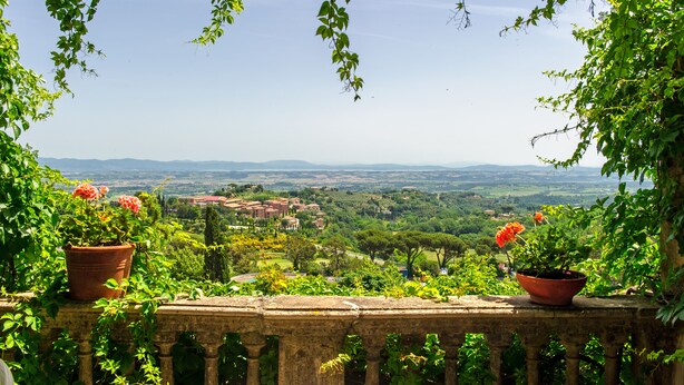 Uma varanda com vista para uma paisagem exuberante, incluindo árvores e edifícios ao longe.