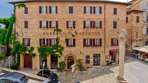 A historic building with the name "ALBERGO MARZOCCO" on the facade, featuring a traditional brick exterior, multiple windows with shutters, and a central entrance.