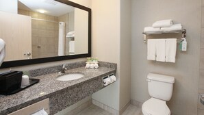 A modern bathroom with a granite countertop, two sinks, a large mirror, a toilet, and a towel rack. - Holiday Inn Express Fort St John by IHG (Fort St. John)