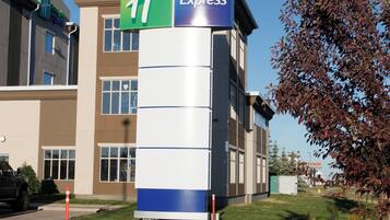 Un bâtiment de l'hôtel Holiday Inn Express, avec une enseigne bien visible, un parking et un espace paysager agrémenté de rochers et d'arbustes.