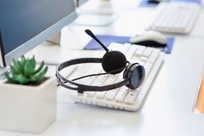 Un auricular sobre un escritorio con un teclado y una pequeña planta en maceta.