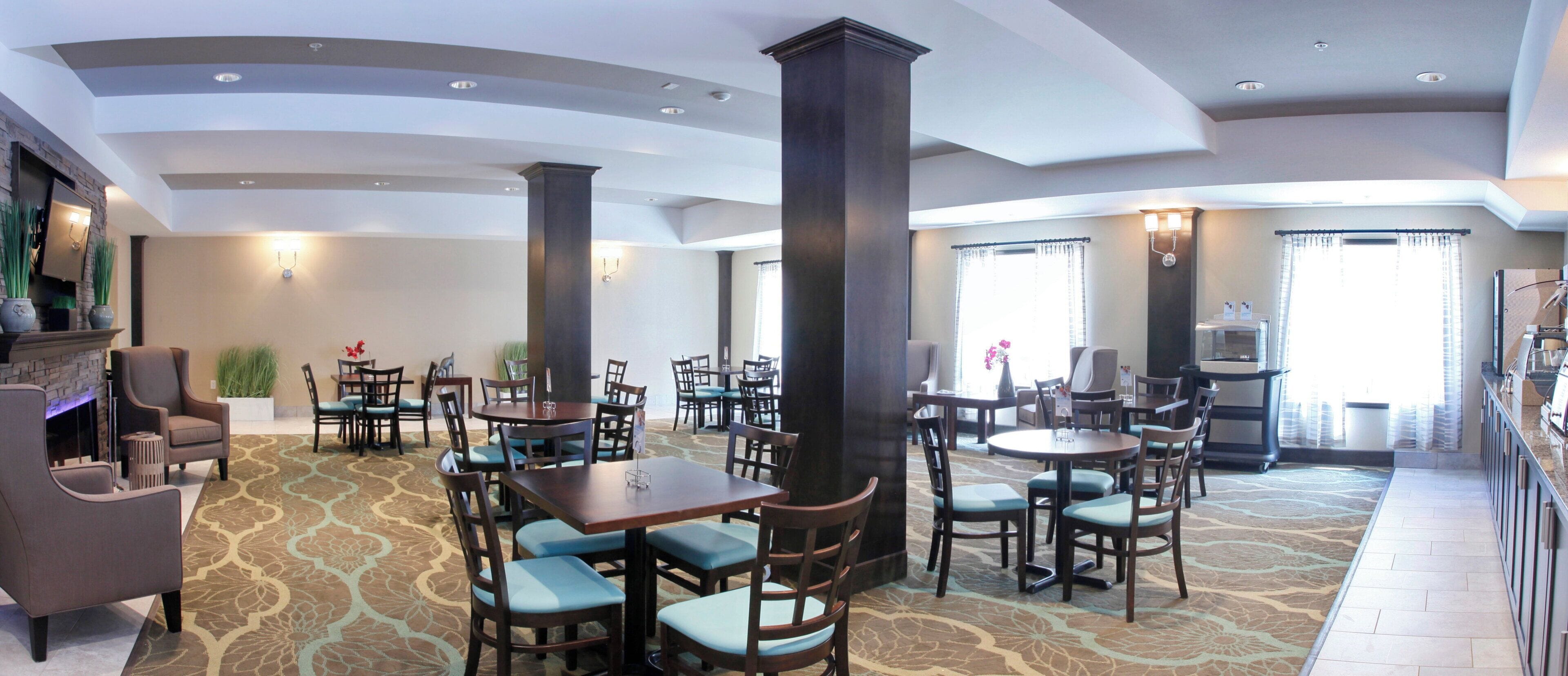 A hotel lobby with multiple seating areas, a fireplace, and a coffee station.