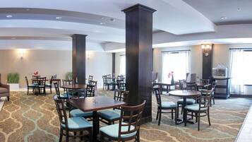 A hotel lobby with multiple seating areas, a fireplace, and a coffee station.