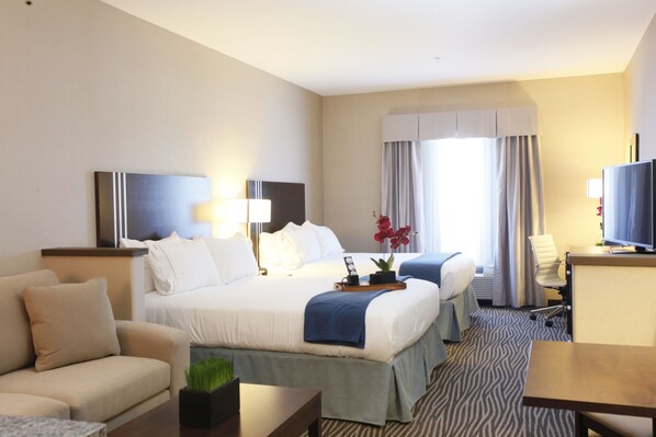 Habitación de hotel con una cama grande, un sofá, un escritorio y una televisión.