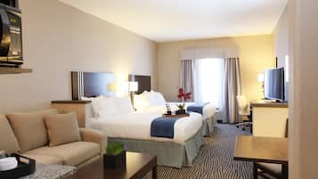 A hotel room with a bed, a sofa, a desk, and a television.