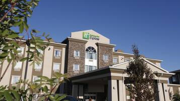 Un hotel Holiday Inn Express con un diseño moderno, que cuenta con un letrero llamativo en el techo y una entrada cubierta.