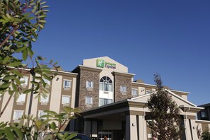 Un hotel Holiday Inn Express con un diseño moderno, que cuenta con un letrero llamativo en el techo y una entrada cubierta.