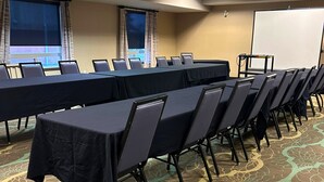 A conference room with a long table, chairs, a projector screen, and a carpeted floor. - Holiday Inn Express Fort St John by IHG (Fort St. John)