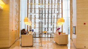 Eine moderne Lobby mit Schachbrettmuster-Boden, einem Empfangstresen und einer Wand mit vertikalen Paneelen.