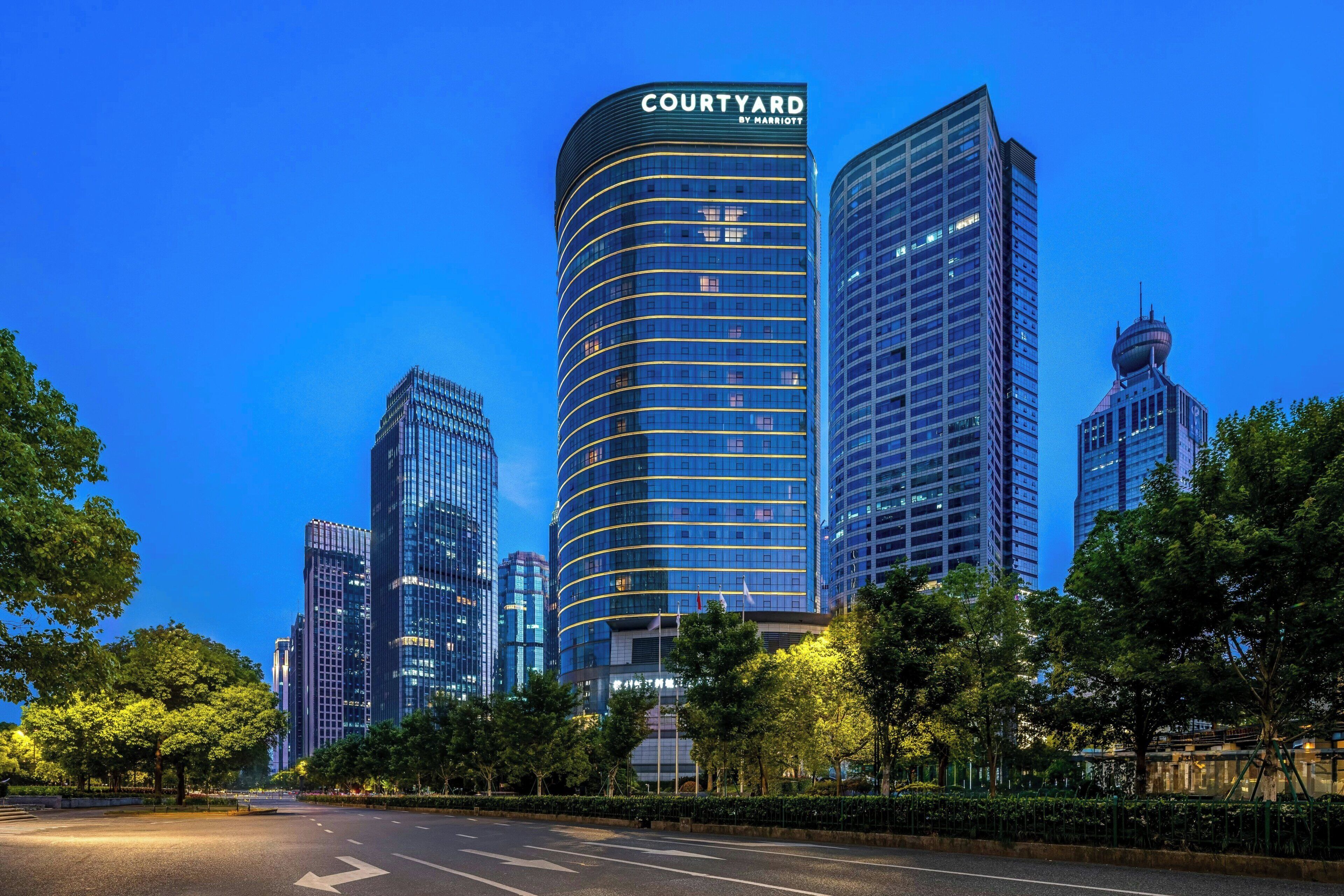 A modern hotel with a curved facade, multiple floors, and a prominent sign.
