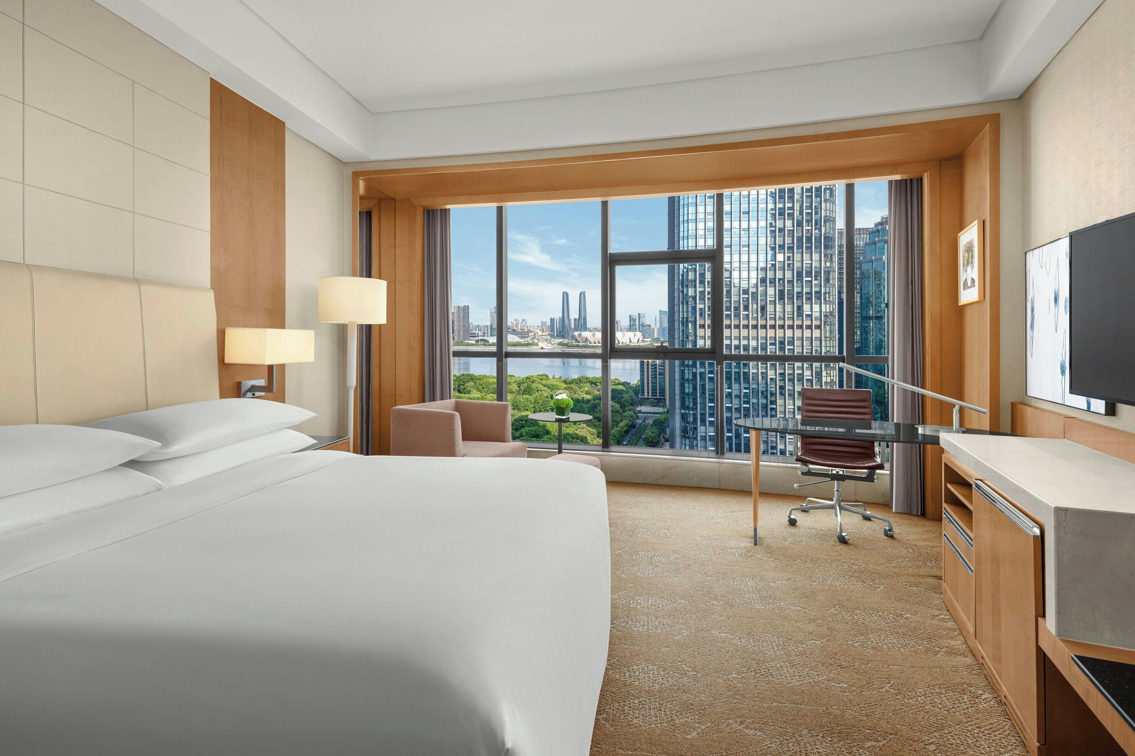 A hotel room with a large bed, a desk, a chair, and a television.