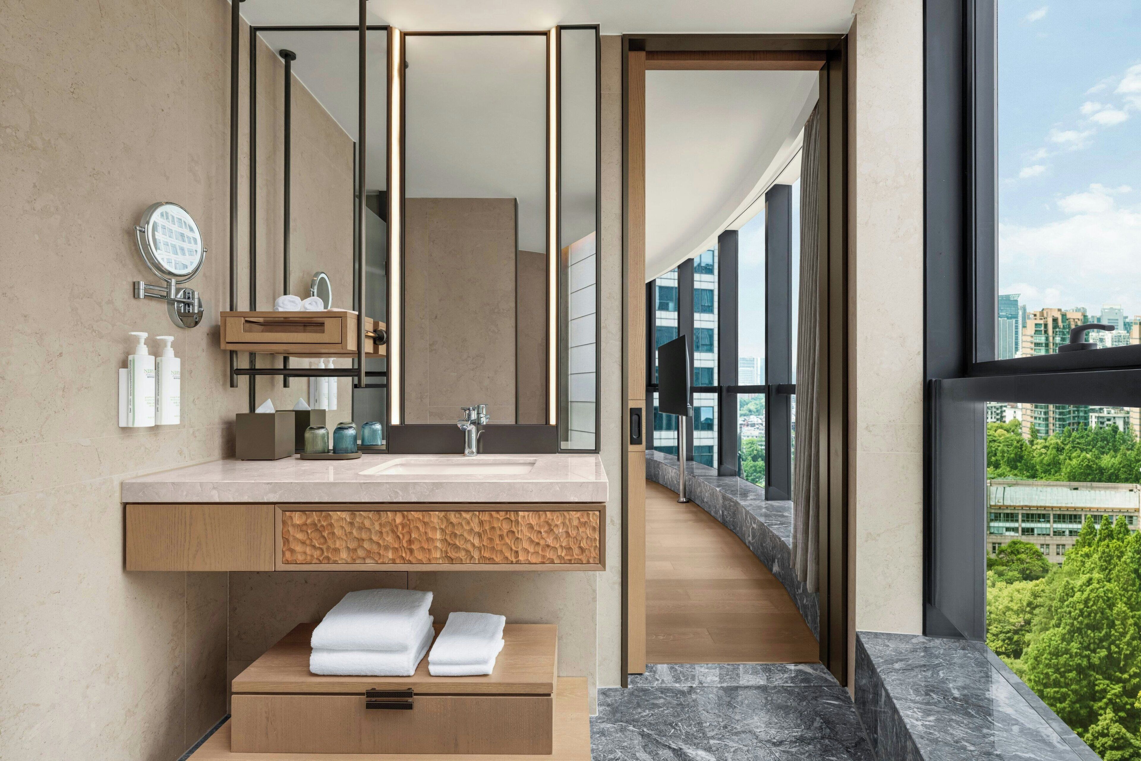 A modern bathroom with a large mirror, a sink, and a vanity with storage.