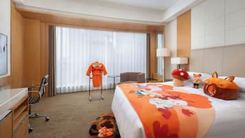A hotel room with a bed, a desk, a chair, a lamp, and a window with curtains.