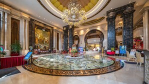 A grand lobby with a large chandelier, marble flooring, and classical architecture.