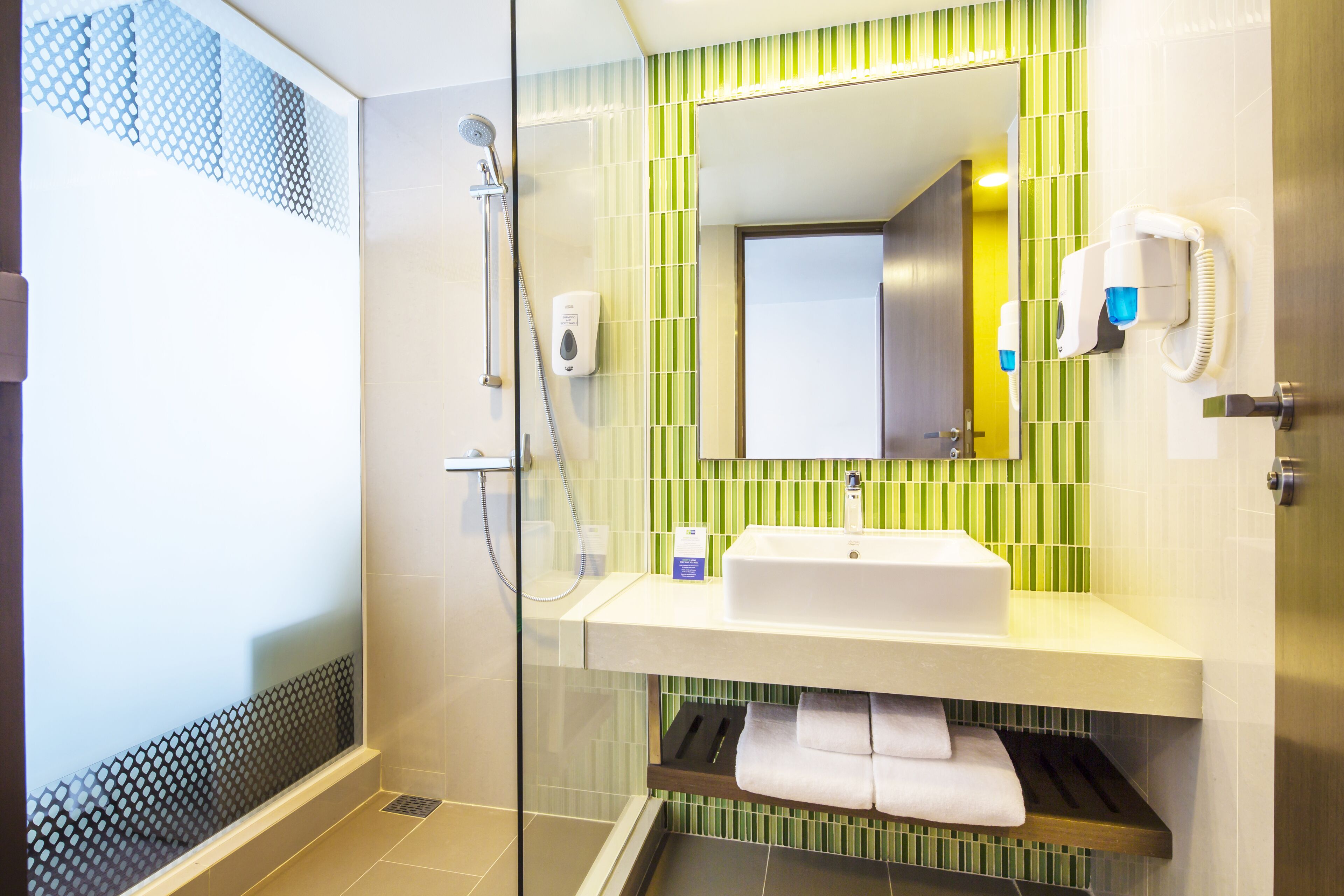 A modern bathroom with a glass shower enclosure, a white sink, and a mirror above it.