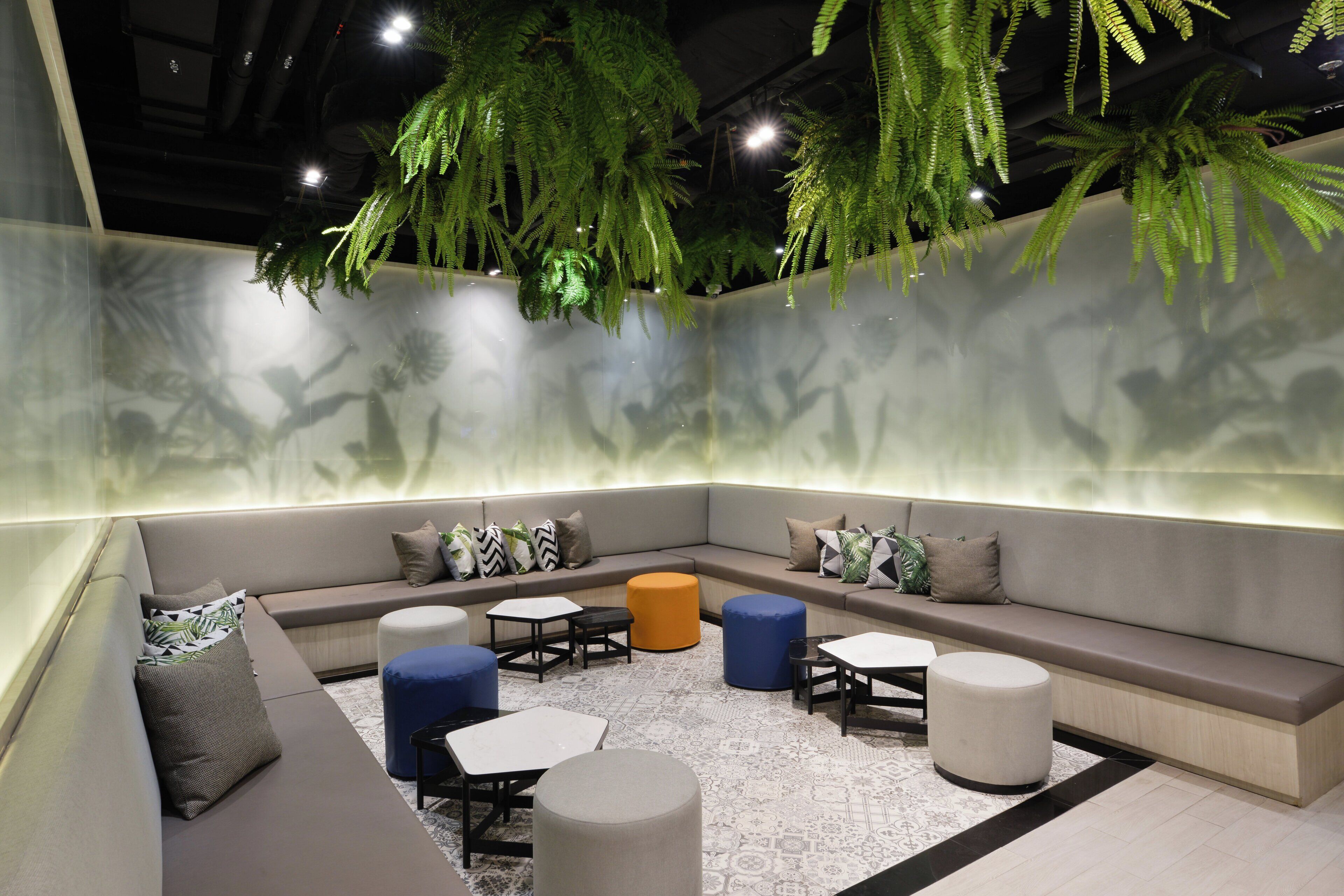 A modern lounge area with a sofa, ottomans, and tables.