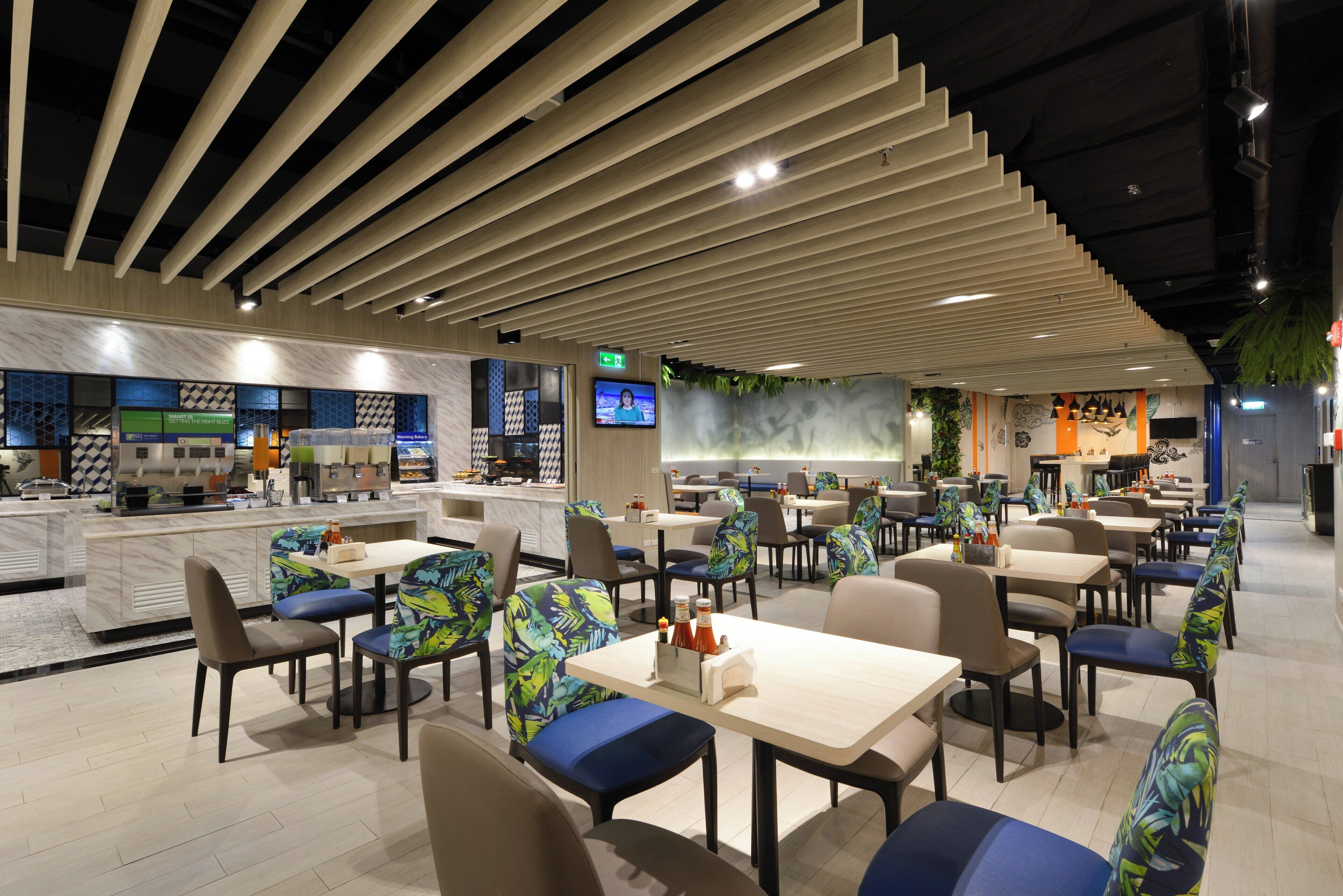 Un interior de restaurante moderno con mostrador, zona de asientos y una pantalla de televisión.